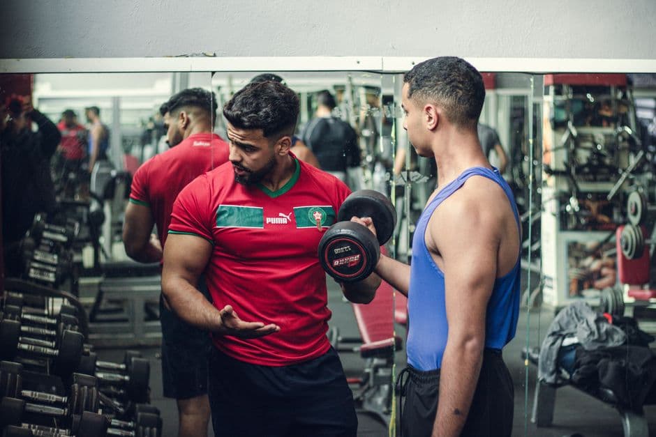 A trainer coaching a client with dumbbells