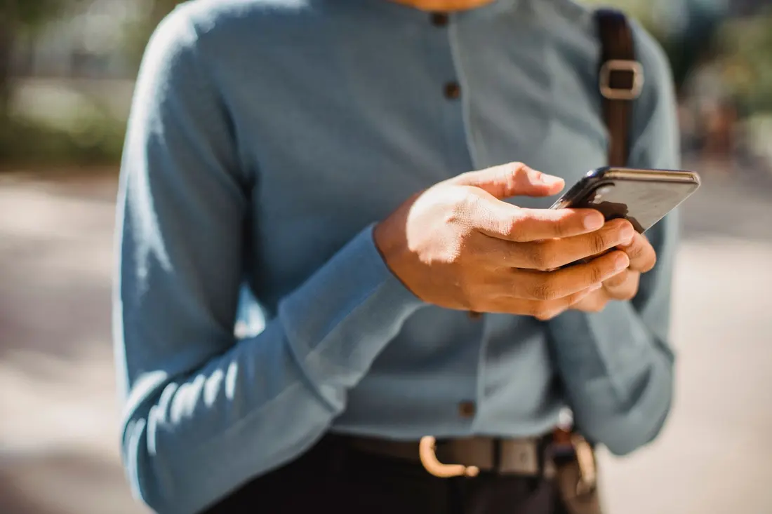 A person standing outside typing a message on their phone