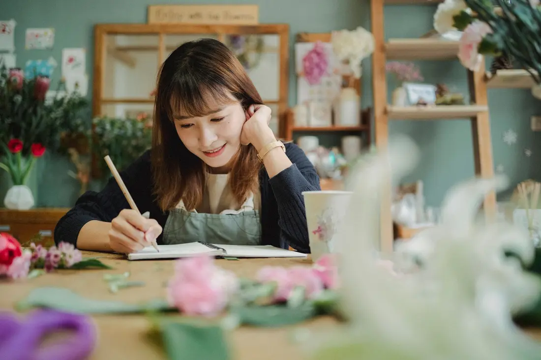 A florist sitting at her counter writing an order in a notebook